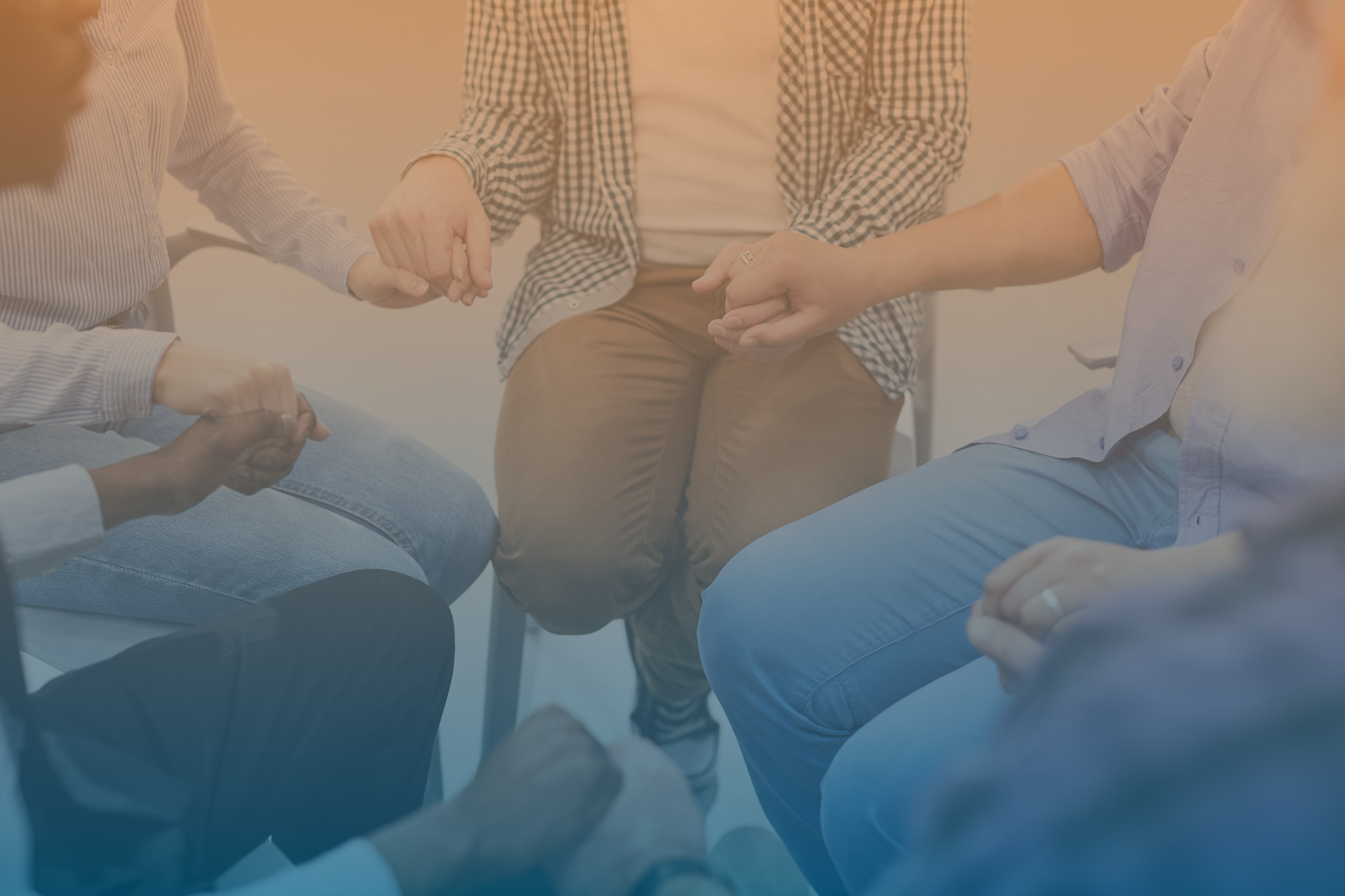 Small group is sitting in chairs in a circle and holding hands