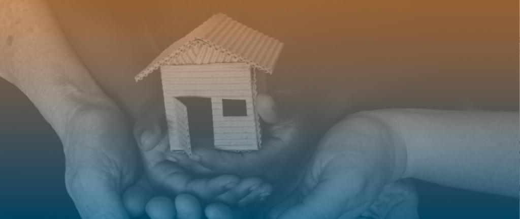 A pair of hands holding a miniature house structure