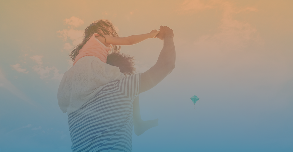 Father holding daughter playing with a kite